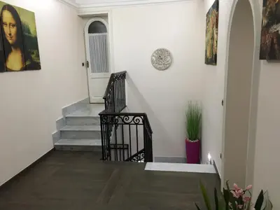 a stairway with a black railing and a clock on the wall at Villa Matissa in Rome