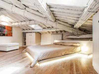 a bedroom with a large bed and wooden floors at Spanish Steps Luxury Penthouse in Rome