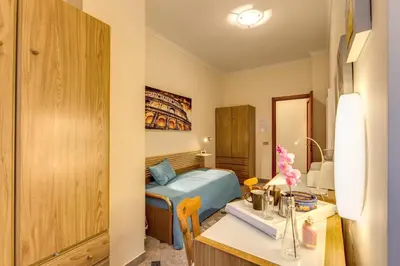 a small room with a bed and a desk with a desk at Residenza Amoroma in Rome