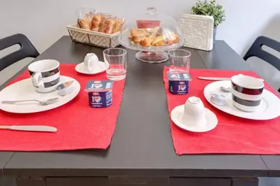 a black table with red placemats and cups and plates of food at B&B Gallia's Rooms in Rome