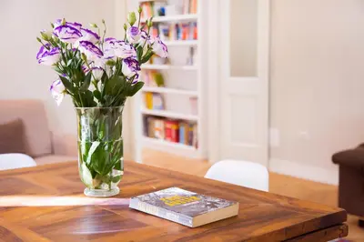 a vase of purple flowers and a book on a table at Casa Tommasina in Rome