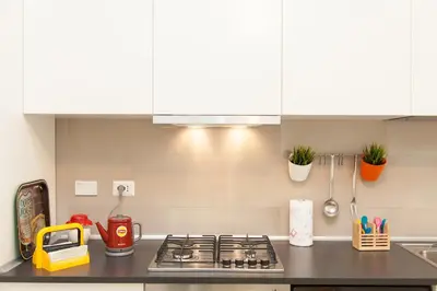 a kitchen counter with a stove top and white cabinets at Lovely House Rome in Rome