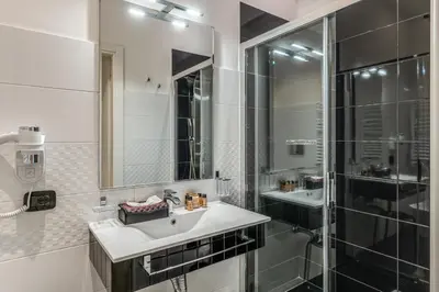 a white bathroom with a sink and a shower at Operà Suites Pinciana in Rome