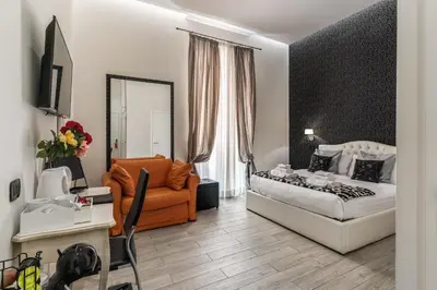 a bedroom with a bed and a chair and a couch at Operà Suites Pinciana in Rome