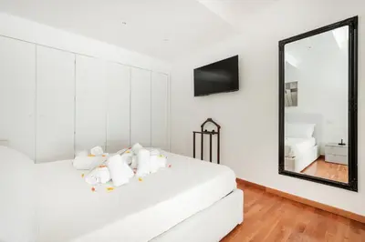 a bedroom with a white bed with a mirror at HOME SWEET HOLIDAY srl in Rome