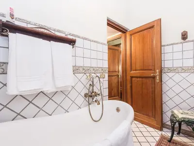 a bathroom with a white tub and a wooden door at Apartment Spanish Steps by Interhome in Rome