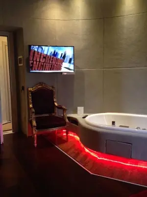 a bath tub in a room with a chair and a tv at MDM Guesthouse in Rome