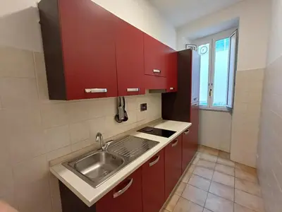 a kitchen with red cabinets and a sink at Apollo Apartments Colosseo in Rome