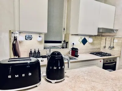 a kitchen with white cabinets and black appliances on a counter at Campo dei Fiori modern apartment with terrace in Rome