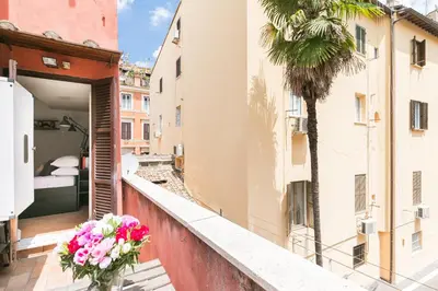 a vase of flowers on a balcony with a palm tree at Xystum in Rome