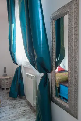 a mirror next to a bed with blue curtains at Letto e Latte Roma Guest House in Rome