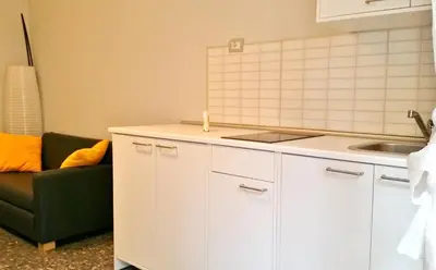 a kitchen with white cabinets and a green couch at Romulea Guest House in Rome
