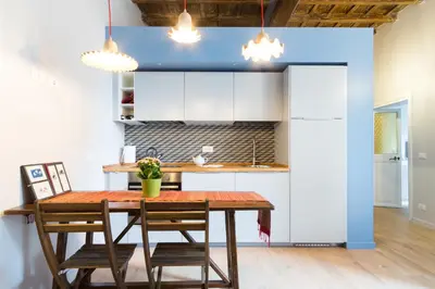 a kitchen with white cabinets and a wooden table and chairs at Ideal Apartment D'Ascanio, Piazza Navona in Rome