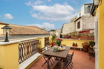 a balcony with a wooden table and chairs at Trevi Charming Penthouse in Rome