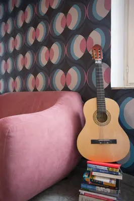 a guitar sitting on a stack of books next to a couch at Sarah's House - Tourist Accommodation in Rome