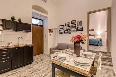 a kitchen and living room with a table with flowers on it at Loft in San Pietro in Rome