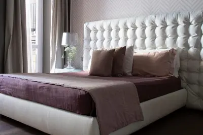 a bed with a large white headboard in a bedroom at Le Quattro Dame Luxury Suites in Rome