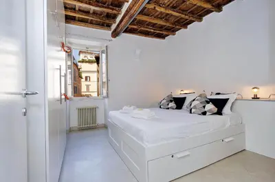 a white bedroom with a white bed and a window at Reginella in Rome