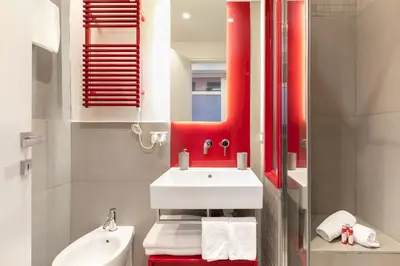 a bathroom with a white sink and a red mirror at Living RHome - Condotti Apartment in Rome