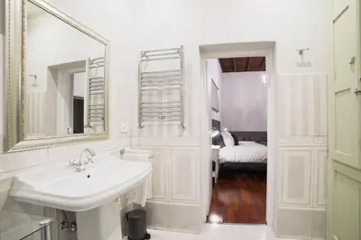 a white bathroom with a sink and a mirror at La Maison Dell'Orologio in Rome