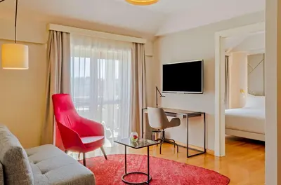 a living room with a couch and a red chair at NH Collection Roma Giustiniano in Rome