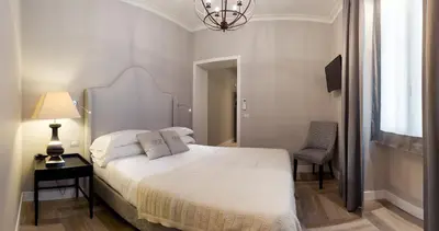 a bedroom with a white bed with a lamp and a chair at Deseo Home Guest House in Rome