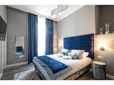 a bedroom with a large bed with a blue headboard at Lea Luxury Rooms in Rome