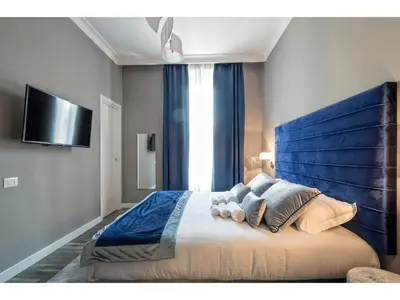 a bedroom with a large bed with a blue headboard at Lea Luxury Rooms in Rome