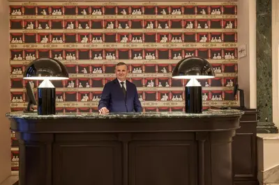 a man in a suit standing behind a bar at Mascagni Luxury Rooms & Suites in Rome