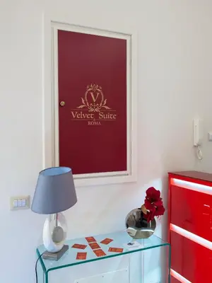 a table with a lamp and a sign on a wall at Velvet Suite in Rome