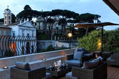 a patio with chairs and tables and an umbrella at Hotel Degli Artisti in Rome
