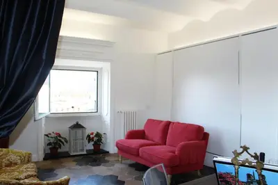 a red couch in a living room with a window at La Rosa del Vaticano Luxury Apartment in Rome