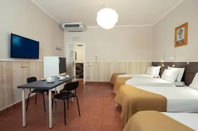 a hotel room with four beds and a table and a tv at Budget Rooms Des Arts in Rome