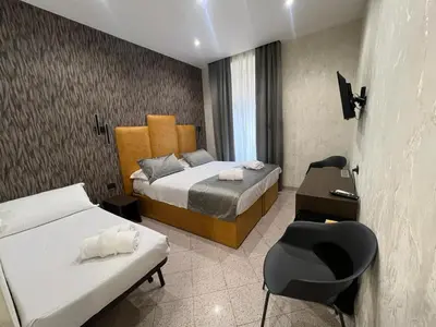 a bedroom with two beds and a desk and a chair at Hotel Ercoli House in Rome