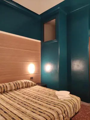 a bedroom with a bed with blue walls at Hotel Milazzo Roma in Rome