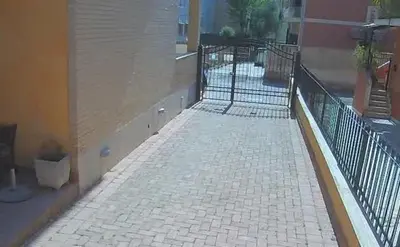 a brick sidewalk next to a building with a fence at La Piazzetta di Roma in Rome