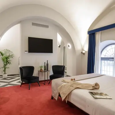 a bedroom with a bed and two chairs and a flat screen tv at Hotel Monte Cenci in Rome
