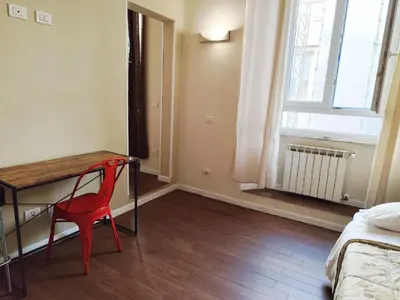 a red chair sitting at a desk in a room with a window at Milazzo23 Guesthouse in Rome