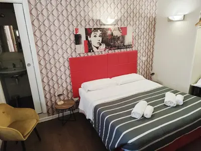 a small bedroom with a bed with a red headboard at Milazzo23 Guesthouse in Rome