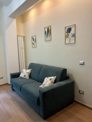 a green couch in a living room with two pillows at Casa Blaserna nel Cuore dello Shopping a Marconi e Trastevere in Rome