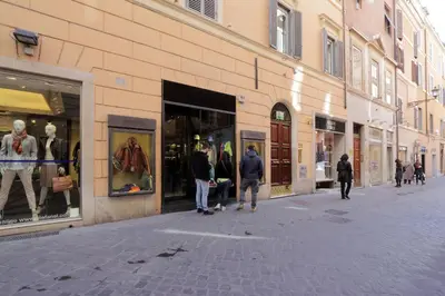 a group of people walking down a street in front of stores at Frattina Family Romantic Superior Suite in Rome