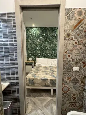 a bedroom with a bed in a room with a wall at LUXOR ECO ROMA CASA E APPARTAMENTO PER VACANZE IN CENTRO Piazza Bologna, Colosseo, Piazza di Spagna, Vaticano, San Pietro, Sapienza, Fontana di Trevi, Piazza Navona, Trastevere, Tiburtina, Termini, Aeroporto in Rome