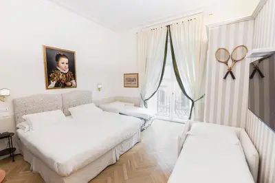 a white room with two beds and a window at Relais Donna Lucrezia in Rome