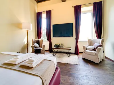 a bedroom with a bed and two chairs and a tv at Domus Corsini in Rome