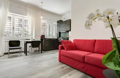 a living room with a red couch and a kitchen at Porta Latina Suite - Private Apartment Rome's Center in Rome