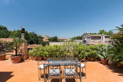 a patio with a table and chairs on a roof at Trastevere Charming Penthouse in Rome
