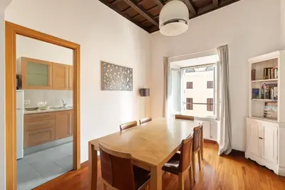 a dining room with a wooden table and a kitchen at Farnese Apartment 1870 in Rome
