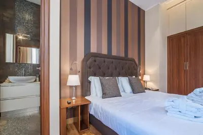 a bedroom with a bed and a bathroom with a sink at 900 Apartments Lazio, Emilia & La Corte in Rome