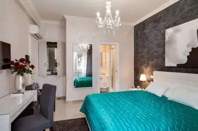 a bedroom with a green bed and a desk and a chandelier at Dreamsrome Suites in Rome