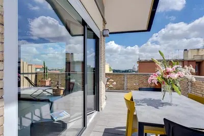 a balcony with a table with flowers on it at Rome as you feel - Vatican Terrace Apartments with View in Rome